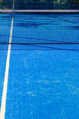 View of a padel court with open doors and bright blue playing surface in the afternoon sun
