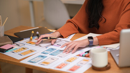 Female designer analyzing mobile app layouts and brainstorming improvements in a modern workspace.
