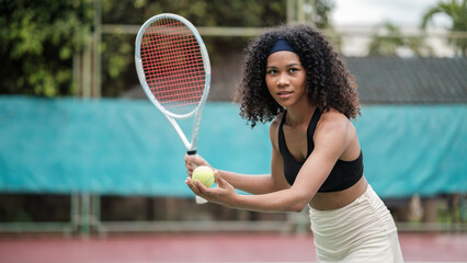 Athletic woman in sportswear on a sunny tennis court while preparing for a serve, fitness, sport,...