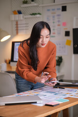 Focused UX UI designer reviewing mobile app prototypes at her workspace.