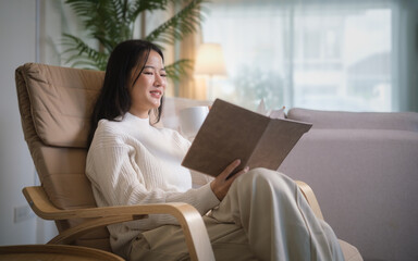 Calm and content woman sitting in an armchair with a book and a warm drink.
