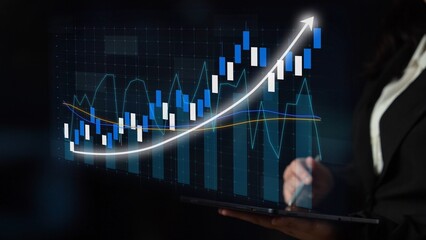 A business professional works on a digital tablet, analyzing stock market data displayed in charts and graphs, indicating growth trends in a modern workspace. Copula