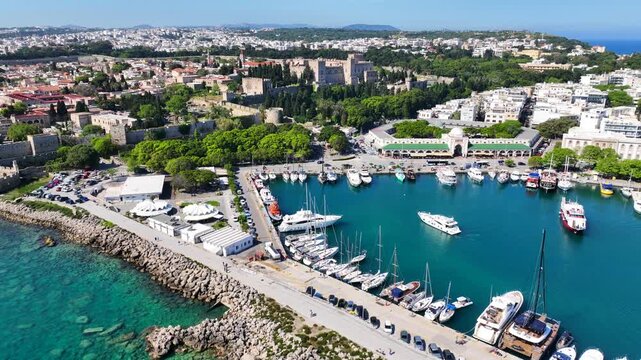 Aerial drone cinematic video of famous waterfront and marina of Mandraki featuring scenic landmark buildings, Rhodes island, Dodecanese, Greece