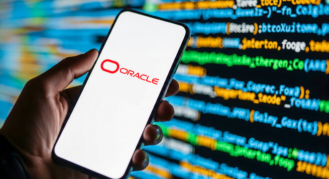 Hand holding smartphone with Oracle logo on screen in front of coding background