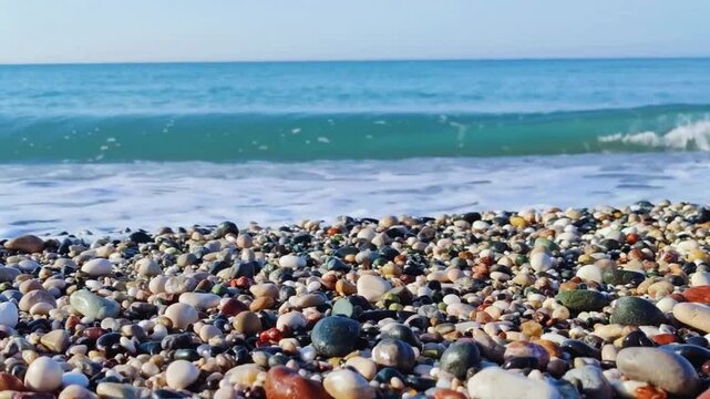 Beautiful close up hd video view of sea waves washing over colorful rounded pebbles on beach white foam tranquil sea landscape texture footage perfect for campaigns websites and projects