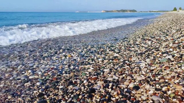 Beautiful close up hd video view of sea waves washing over colorful rounded pebbles on beach white foam tranquil sea landscape texture footage perfect for campaigns