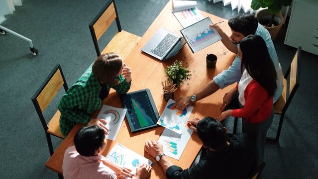 Top view of project manager present financial graph to investors at meeting. Professional marketing team brainstorming financial idea while looking at financial statistic from laptop. Convocation.