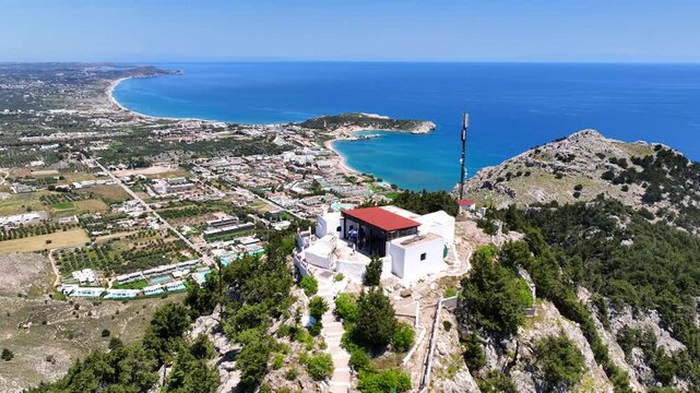 Aerial drone cinematic video of uphill chapel of Panagia Tsambika, overlooking bay of Kolymbia and famous Tsabika beach, Rhodes island, Dodecanese, Greece