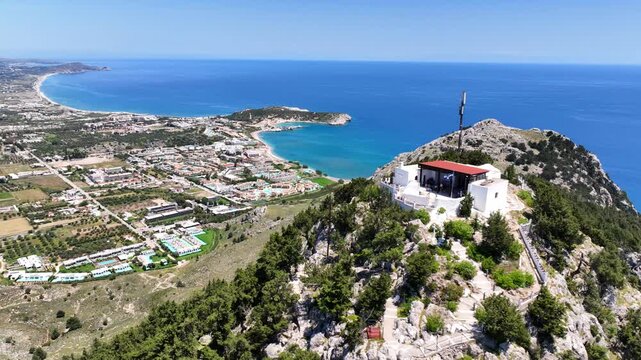 Aerial drone cinematic video of uphill chapel of Panagia Tsambika, overlooking bay of Kolymbia and famous Tsabika beach, Rhodes island, Dodecanese, Greece