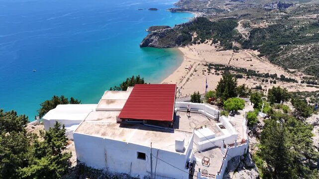 Aerial drone cinematic video of uphill chapel of Panagia Tsambika, overlooking bay of Kolymbia and famous Tsabika beach, Rhodes island, Dodecanese, Greece