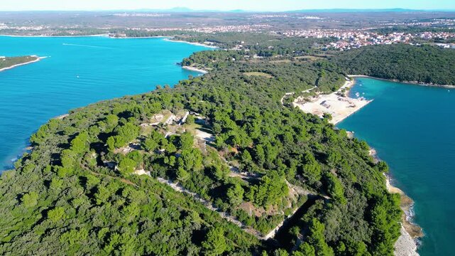 Aerial view of historic Fort Punta Christo near Pula, Croatia, nestled in lush Mediterranean forest, overlooking the clear blue Adriatic Sea and scattered islands.