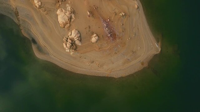 Birds-eye aerial drone hover over greenish lake water with visible bottom and sky reflections, camera moving up Spain