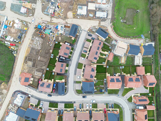 Interesting drone UAV inspection view of newly built homes seen on a sprawling housing development in Britain. Part finished homes can also be seen. Homeowners have moved in.