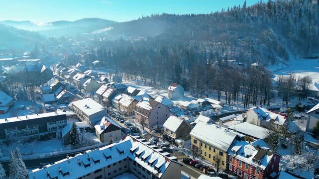 Aerial view of Delnice, Croatia, blanketed in pristine winter snow. Sunlit roofs and frosted forests create a picturesque scene in Gorski Kotar.