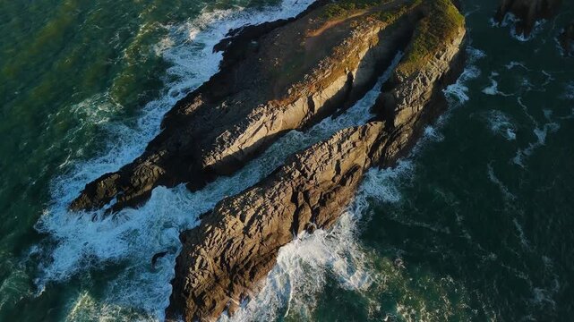 Aerial drone view over sharp coastal cliffs with rocks and crashing ocean waves Spain