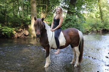 Attraktive junge Frau reitet auf Ihrem Pferd durch kleinen Fluss