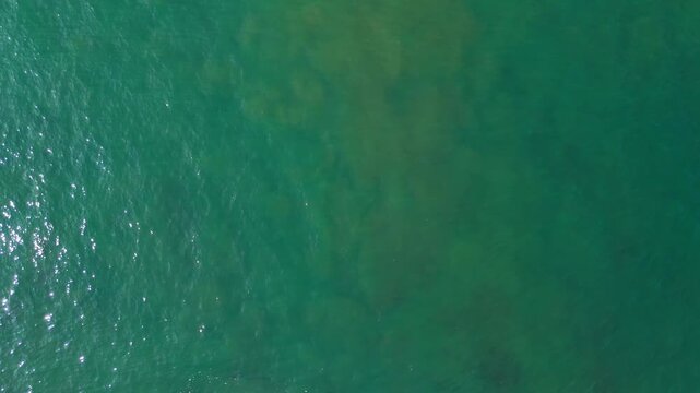 Birds-eye aerial drone view of calm greenish ocean water, Portugal