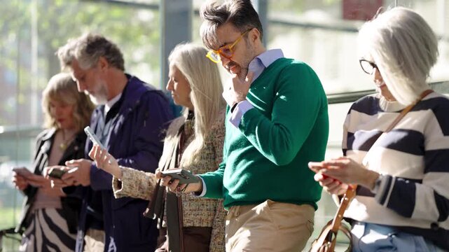 Diverse group of mature and senior people absorbed in their smartphones. Technology addiction and digital dependency concept in modern society