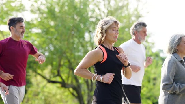 Healthy group of mature friends jogging together in a park. Senior men and women maintaining a fit lifestyle with outdoor cardio exercise