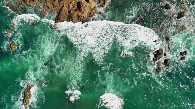 Birds-eye aerial drone view of ocean waves with greenish water and white foam, Portugal