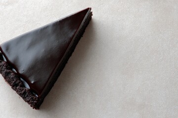 Rich dark chocolate ganache tart slice with crumbly crust rests elegantly on a bright textured background, inviting dessert lovers, copy space