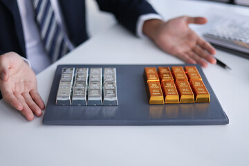 Silver and gold bars on the table. Businessman investing in precious metals gold and silver to diversify portfolios hedge against inflation and currency depreciation.