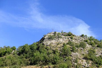 Cross on Rocky Green Hill Under Blue Sky in Lebanon