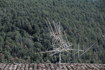 Antenne auf einem Hausdach mit Wald im Hintergrund