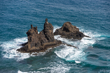 Jagged volcanic sea stacks with blue ocean waves and white surf near Benijo beach on the north coast of Tenerife, Canary Islands, Spain.