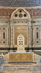 Rome, Italy &ndash; 14 January 2025. In San Giovanni in Laterano, the papal altar features a gold panel with a radiating cross and saints, set before a white inlaid marble throne and patterned apse wall.