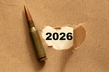 A bullet and torn paper with the date 2026 on a brown background, a symbol of war and peace, strength and pain, threat and hope for change