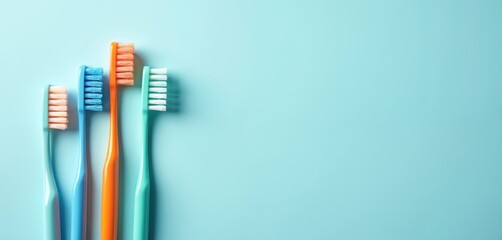 Four colorful toothbrushes stand in a row. Blue, orange, and green brushes are arranged on a pastel cyan background. Oral hygiene tools for daily cleaning.