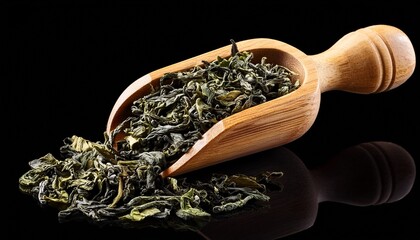 dried green tea leaves in a wooden scoop isolated on black background culinary ingredients