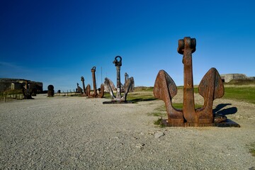 Row of rusty ship anchors under a clear blue sky &mdash; maritime history and nautical heritage concept