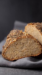 Rustic whole grain bread slices featuring crunchy mixed seed crust presented on dark grey textile backdrop