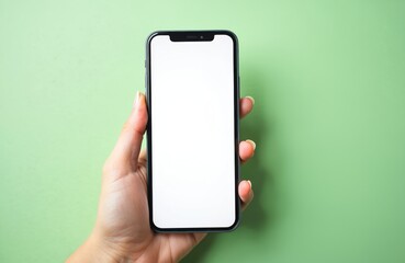 Female hand holds modern smartphone with blank white screen on light green backdrop. Ready for app promotion, website display or ad content. Perfect for tech topics.
