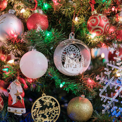 Close-up view of decorated Christmas tree with red, white, and glass ornaments illuminated by...
