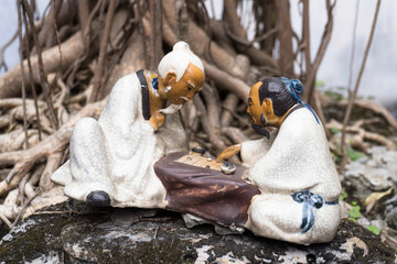 A figurine depicting a scene of two eldery men playing an old board game