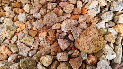 Top-down view of mixed gravel stones, featuring pink feldspar, grey quartz, and irregular earthy fragments
