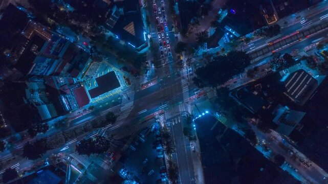 Top down hyperlapse over a busy intersection in Mexico City at night, as the drone ascends to reveal traffic flow, light trails, and the urban grid illuminated by city lights.