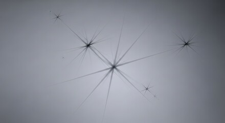 Abstract representation of celestial bodies or starburst effects in a soft, diffused light with a subtle grey gradient background