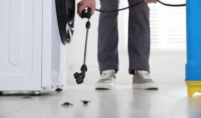 Pest control worker spraying insecticide indoors, closeup