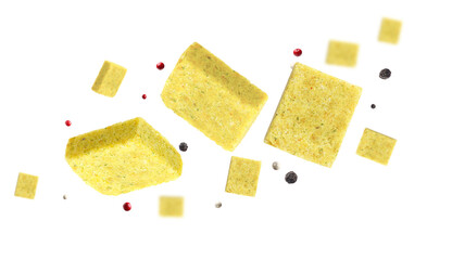 Bouillon cubes and peppercorns flying in air on white background