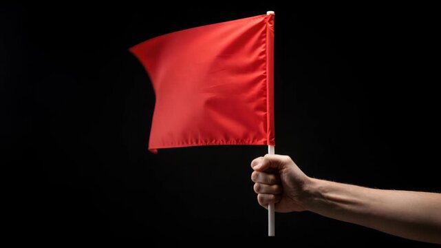 Symbol of Warning: A hand firmly grips a small red flag against a dark backdrop. The simple yet powerful image immediately grabs attention, symbolizing warning, alert, or a signal of caution.