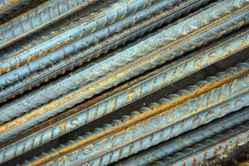 Steel bars used for reinforced concrete construction, have reddish brown spots and a rough texture....