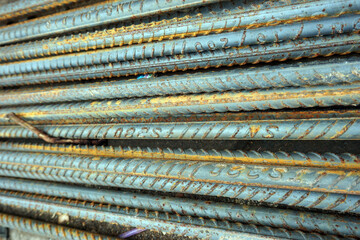 Steel bars used for reinforced concrete construction, have reddish brown spots and a rough texture. This rust forms due to exposure to oxygen and water, which can reduce structural strength if corrosi