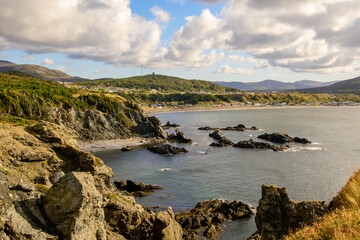 Hiking trail above Trout River village in Gros Morne National Park, with coastal water, hillside path, and homes along the shoreline during fall in western Newfoundland.