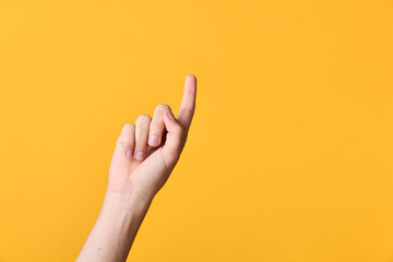 Close up of a hand with the index finger raised, gesturing upward against a bright orange backdrop, emphasizing focus, direction, and a minimal, modern visual cue suitable for banners and tutorials