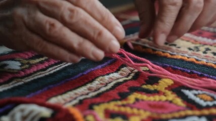 Sajadah Hand-Stitching. Islamic Culture – Ramadhan. The delicate, aged hands of an artisan meticulously hand-stitching colorful patterns onto a new Sajadah (prayer rug) for the season.
