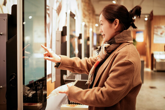 Woman using self-service kiosk in shopping mall